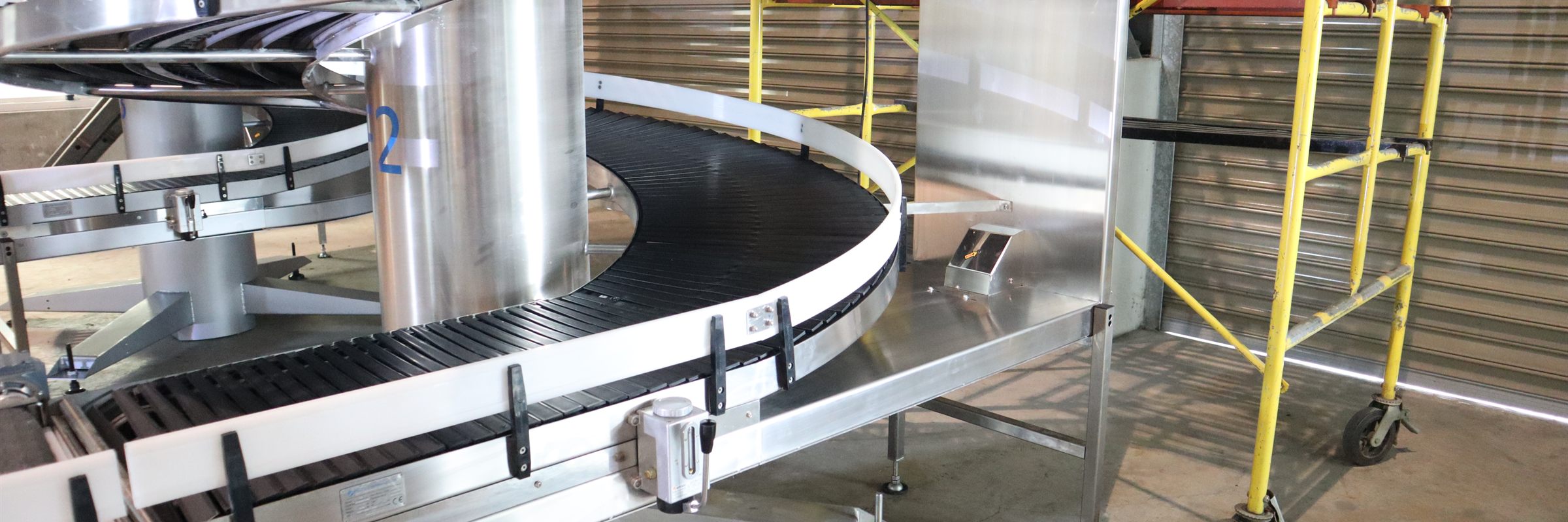 A stainless steel spiral conveyor connected directly into a curve conveyor on the NEXUS factory floor.