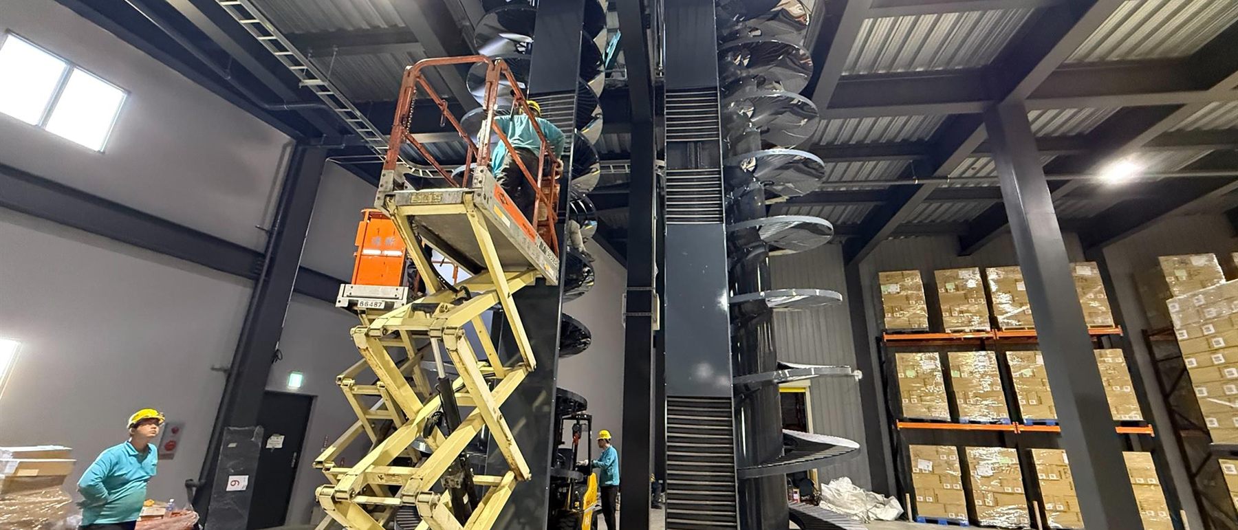 A spiral conveyor installed among racking in a distribution centre.