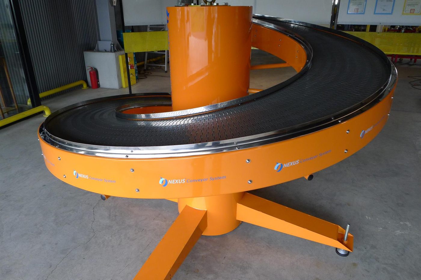 An orange NEXUS spiral curve conveyor in its complete form, a single curved run around a central column.