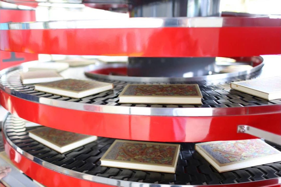 Books travelling on the black slat chain of a red spiral conveyor.