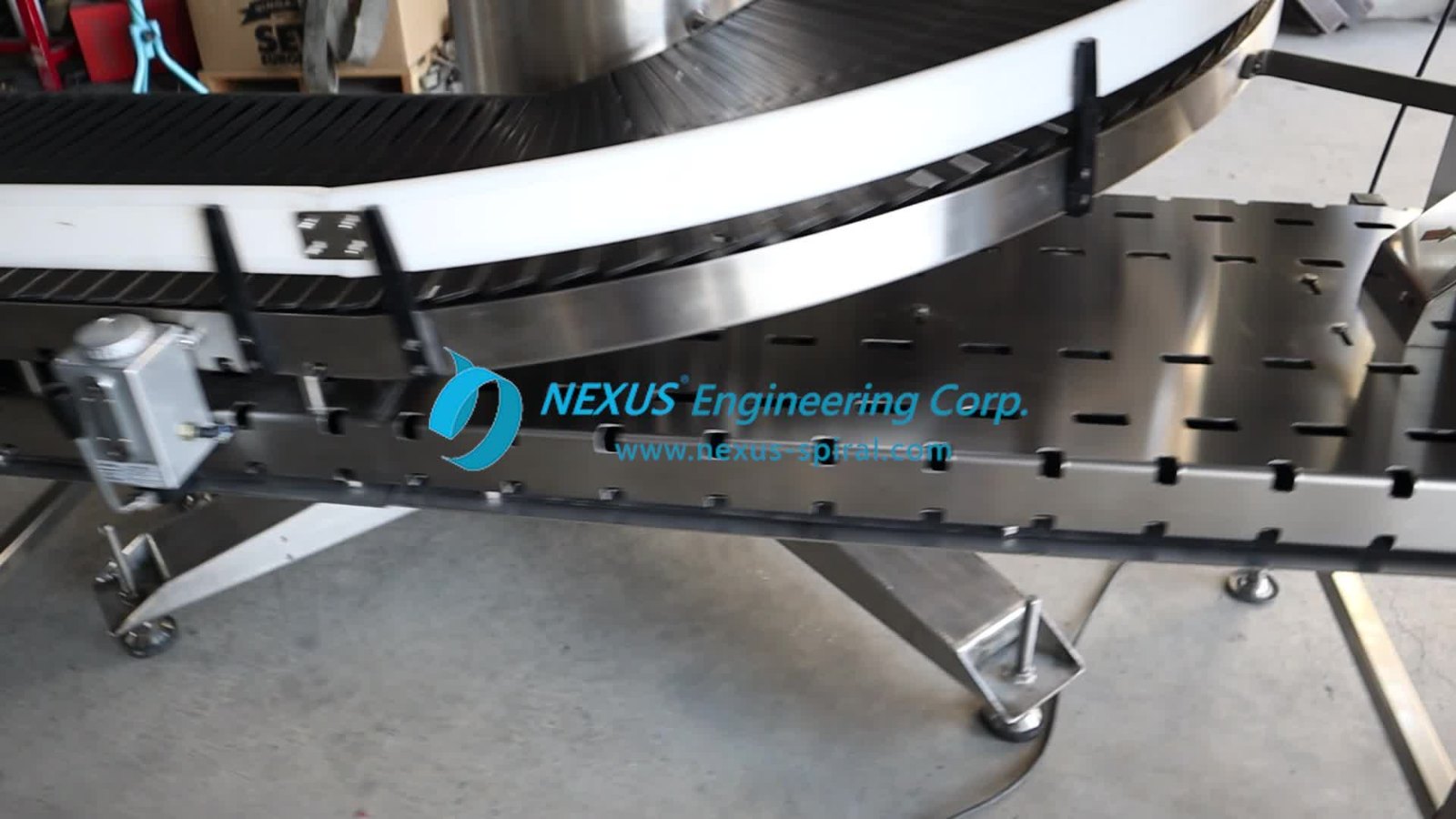 The lower stainless steel structure of a conveyor, perforated with rows of narrow rectangular openings along its length.