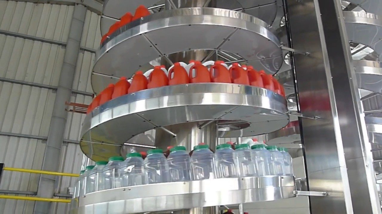 Plastic bottles and jugs on the tiers of a stainless steel spiral conveyor.