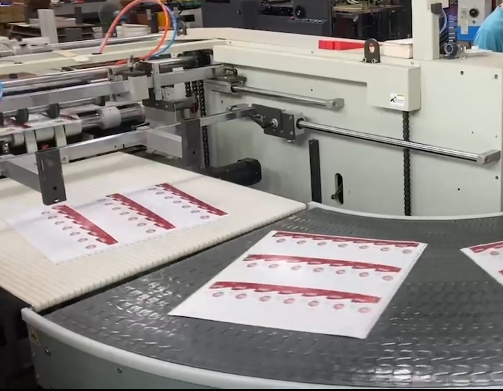 Printed sheets carried on a dark modular belt curve conveyor, leaving a printing machine on a working line.
